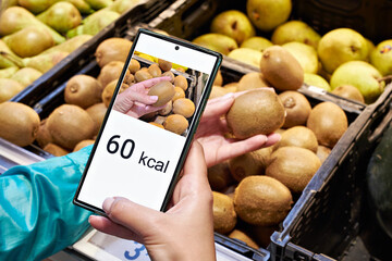 Checking calories on a kiwi fruit in store with smartphone