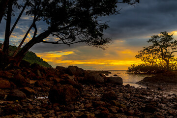 Sunset view at beach with rocks and cloudy sky