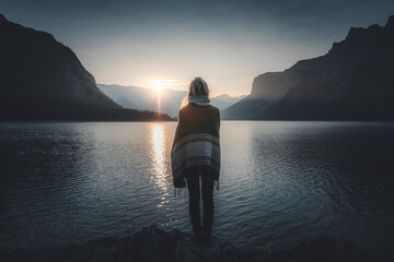 View of a person watching the sun rise over Lake Minnewanka, Alberta, Canada.