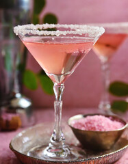 Pink alcohol cocktail with lemon fruit slice, blurred pink background. Bar or restaurant beverage