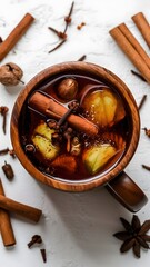 A rustic wooden mug filled with warm mulled cider, infused with spices like cinnamon, cloves, and nutmeg