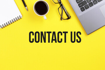 Contact us. Desk with laptop, eye glasses, flower, pen and a cup of coffee. Still life, business, office supplies or education concept.