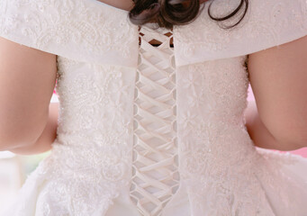 Tying the back of the bride's white evening dress - obrazy, fototapety, plakaty