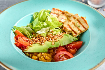 Grilled chicken fillet and avocado salad bowl with fresh veggies on a sun-kissed tabletop