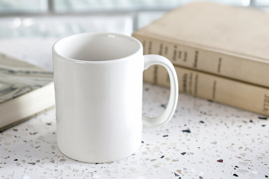 Natural blank white mug POD product mockup minimal empty space on terrazzo table two books background for book lover reader bookworm earthy rural farmhouse boho marketing literary library campaign