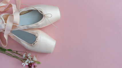 A pair of white ballet shoes are on a pink background - obrazy, fototapety, plakaty