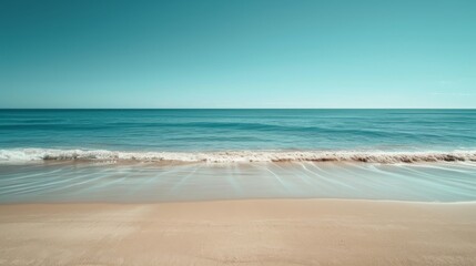 Fototapeta na wymiar Blue ocean waves crashing on a sandy beach under a clear blue sky.