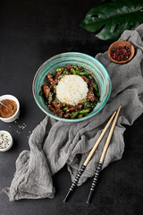 Asian food - boiled rice with fried beef and green beans in ceramic bowl on black stone background. Stir-fried beef with string beans and rice in modern style. Asian food menu in dark backdrop. - 788218503