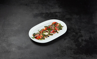 Traditional italian food - caprese salad with mozzarella cheese, tomatoes and pesto sauce. Caprese salad on black concrete background in minimal style. Italian appetizer caprese on dark background - 788218550