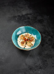 Fancy appetizer of grilled sea scallops in creamy sauce. Roasted sea scallops in cheese espuma in ceramic bowl on black concrete background. Seafood menu. Delicatessen sea scallop on dark stone table. - 788218915