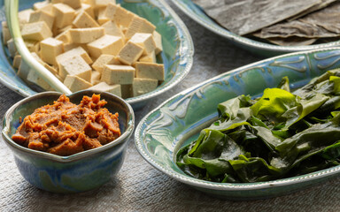 Ingredients for vegan miso soup: miso paste, dried kombu seaweed, rehydrated wakame seaweed, tofu.