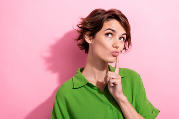 Photo of charming doubtful young woman dressed green shirt finger cheekbone looking empty space...