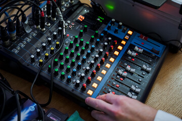 Person using mixer on wooden table with audio equipment