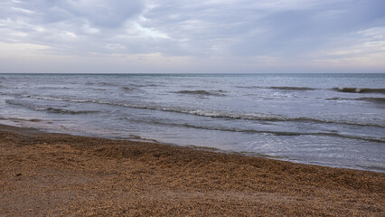 A beach with small shells and the sea. The coast of the Caspian Sea. Cool weather on the coast. A...
