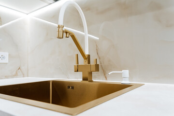 Square sink in bronze, gold faucet in the kitchen, designer sink in yellow metal.