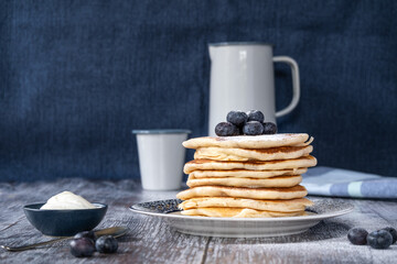 Straigh on view of a stack of pancakes with icing sugar and blueberries