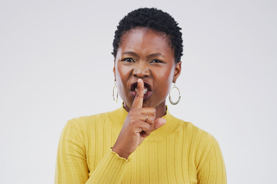 Portrait, secret and shush with angry black woman in studio isolated on gray background for mystery. Face, finger on lips and warning with emoji hand gesture of confident person to whisper gossip