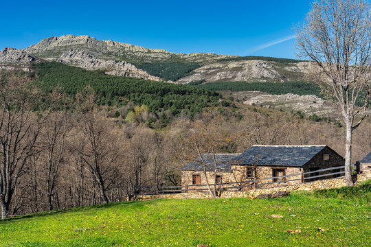 Idyllic image with small stone houses next to the mountains in a green meadow, Guadalajara, Spain.