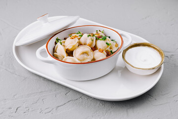 Delectable dumplings in ceramic pot on white plate