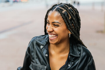 Radiant woman with braided hair laughing in a casual outdoor setting.