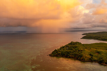 Dramatic view of rain clouds over the ocean. Black and yellow clouds with rain. Sunset. Island Fiji.