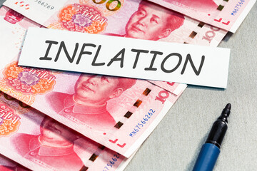 China business economic recession concept. Yuan banknotes and list with INFLATION word.