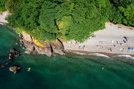 Aerial top view of Batumi beach lined with lush greenery and clear waters. 