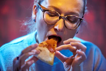  45 year old woman with glasses eats pizza © dvoinik