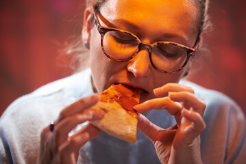 45 year old woman with glasses eats pizza