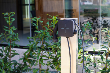 Home station for charging electrical vehicles. photo of an electric power station with outlet and charger for parked cars in front of the house.