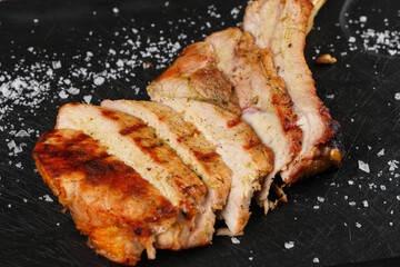 Pork chop steak. Close up photo with a pork barbecue steak on a black grill plate with salt spread around it.