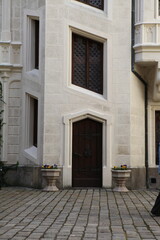 Vertical symmetrical shot of a dark wooden door in an old white building on city streets