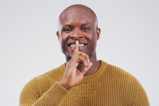 Portrait, smile and shush with private black man in studio isolated on gray background for mystery. Face, finger on lips and silent with emoji hand gesture of happy bald person to whisper gossip