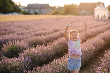 Children walking and enjoying fun the time. A smiling kid running among lavender flowers with sunlight on a summer day. A child girl goes into a lavender field at sunset.