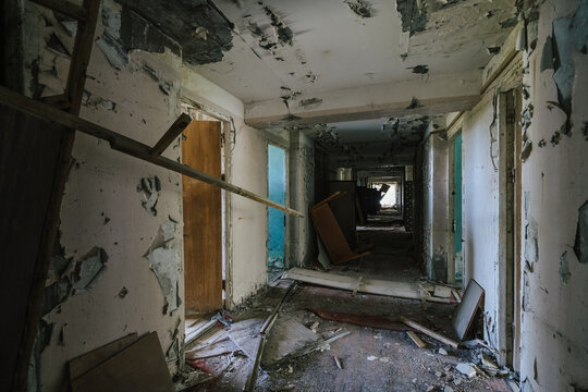 Hallway of desolation in abandoned building, peeling paint and debris speak of decay.