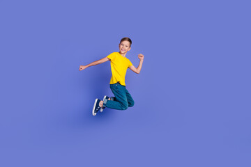 Fototapeta na wymiar Full length photo of cheerful optimistic active boy wear stylish yellow clothes fly air yeah success isolated on violet color background
