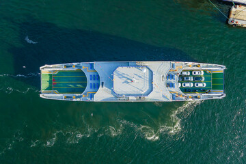 Passenger ferry boat with cars arriving on pier. Sea logistics and transportation. Aerial top down view