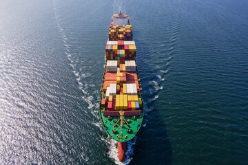 Large Container Ship carrying intermodal cargo cruising across the Sea fully loaded, Aerial view
