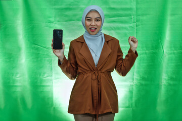 Happy asian woman wearing hijab and blazer showing mobile phone blank screen and hand gesture...