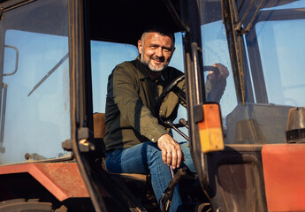 Fototapeta na wymiar Portrait of satisfied farmer sitting in a tractor.