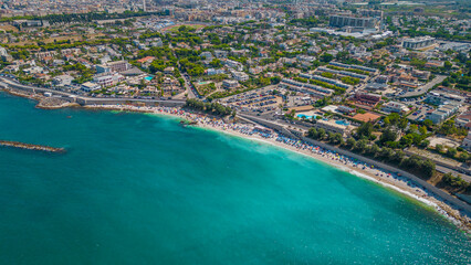 Top view, splendid aerial view of some people relaxing on a beautiful beach washed by the sea. Bisceglie (Apulia, Italy)