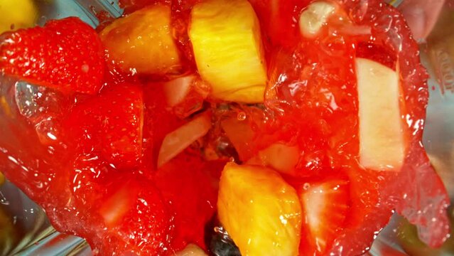 Super slow motion of mixing pieces of fruit and vegetables in blender, camera movement, top shot. Filmed on high speed cinema camera, 1000 fps.