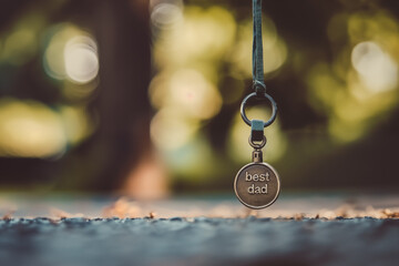 A metal badge hanging on a cord with the inscription "best dad"