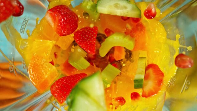 Super slow motion of mixing pieces of fruit and vegetables in blender, camera movement, top shot. Filmed on high speed cinema camera, 1000 fps.