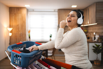 Woman singing while hanging the laundry on drying rack at home