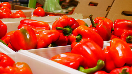 Lots of ripe red bell peppers on a market counter