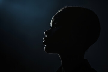 Silhouette of African american child in dark, close up profile portrait
