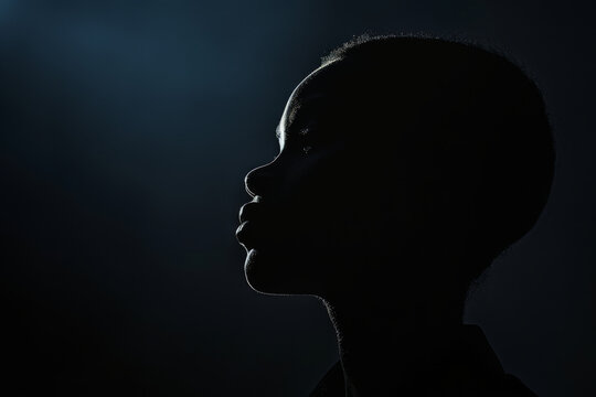 Silhouette of African american child in dark, close up profile portrait