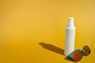 Blank white spray bottle with sunglasses in direct sunlight