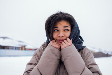 Close up of beautiful mixed race girl feels cold and wraps herself up in knitted woolen scarf.